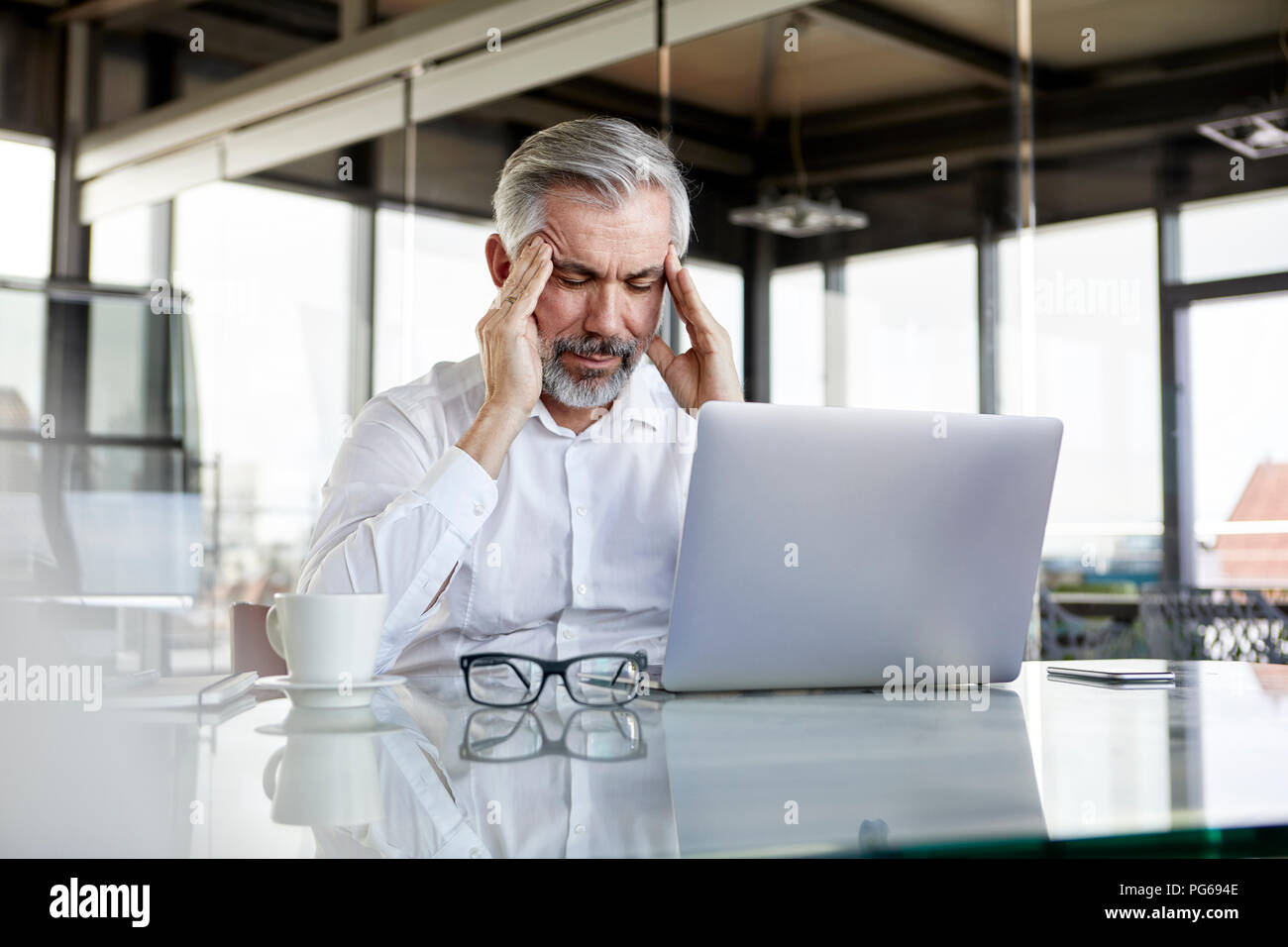 Businessman avec des maux sitting at desk in office Banque D'Images