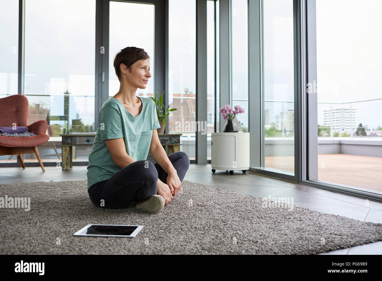 Femme assise sur le sol à la maison avec tablet à la porte du balcon de Banque D'Images