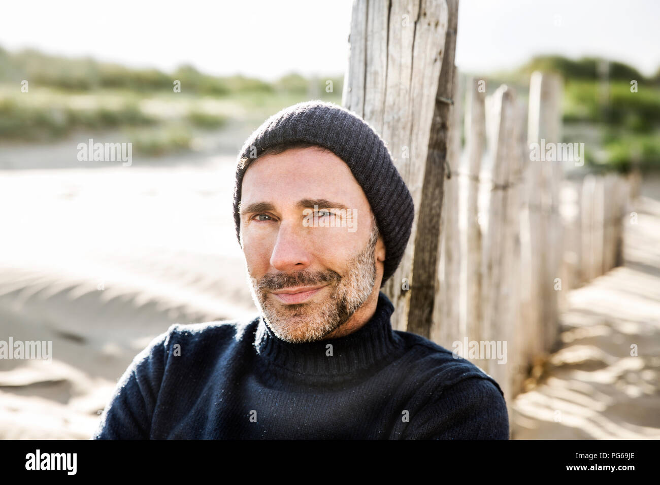 Portrait of smiling man at clôture sur la plage Banque D'Images