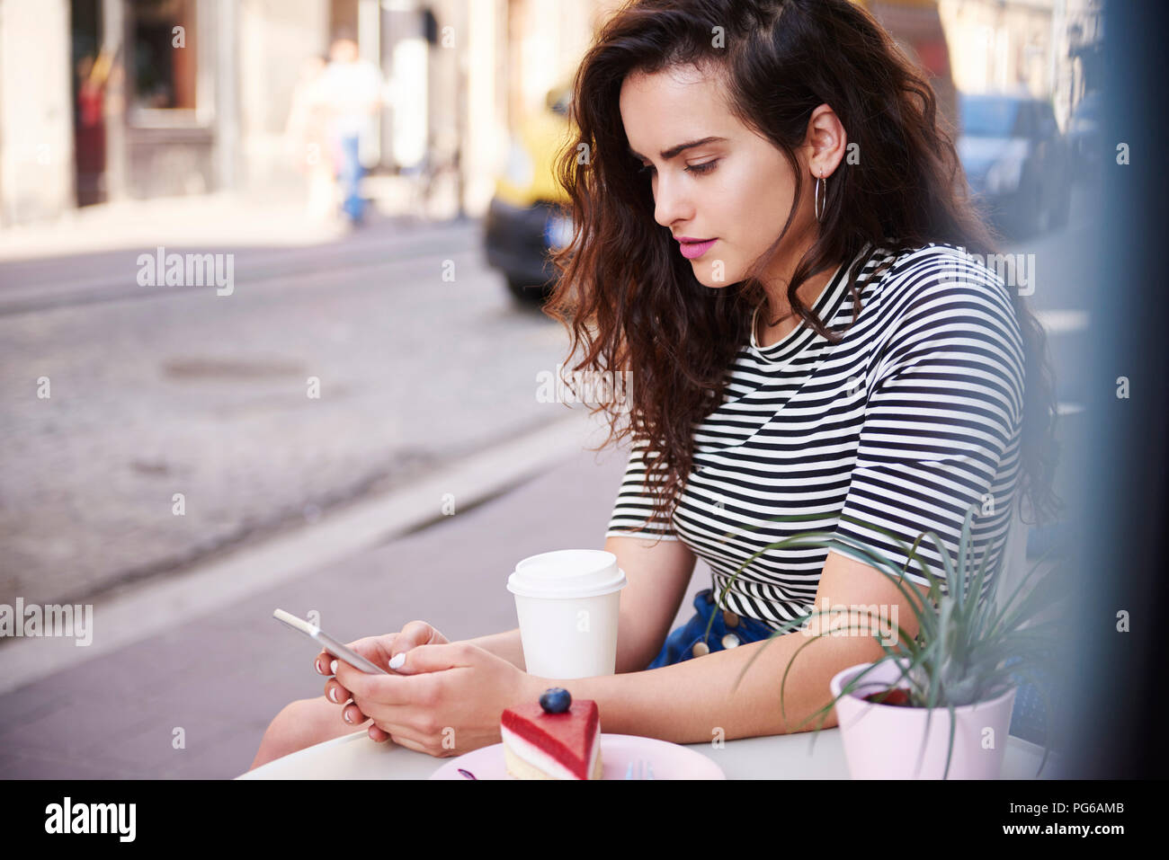 Young woman using cell phone at outdoor cafe dans la ville Banque D'Images