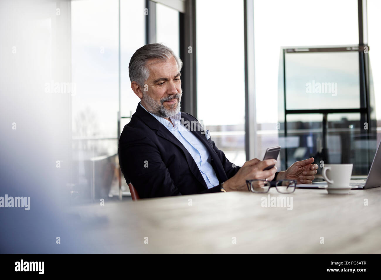 Businessman using cell pohone at desk in office Banque D'Images
