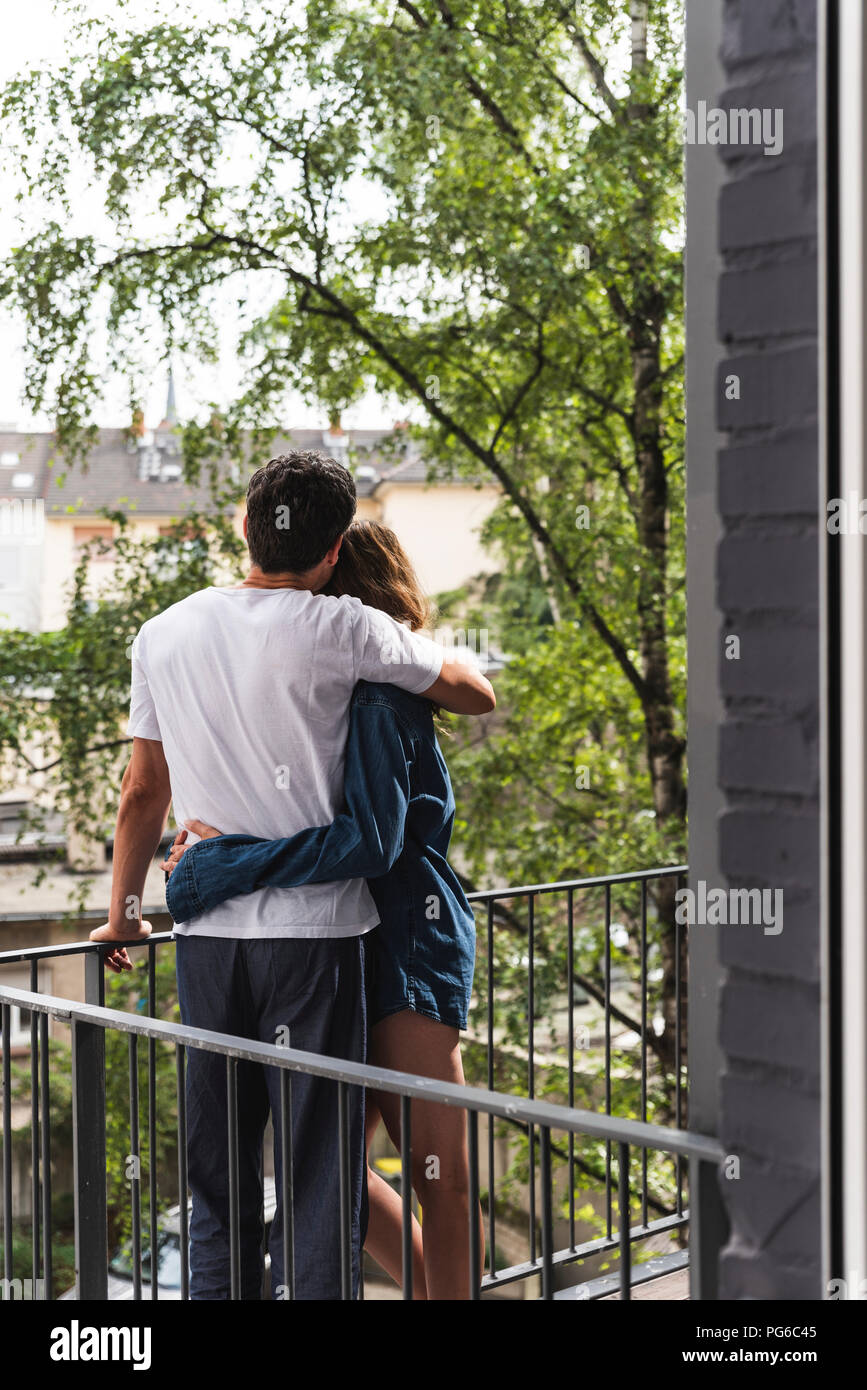 Vue arrière du couple dans des chemises de nuit debout sur balcon hugging Banque D'Images