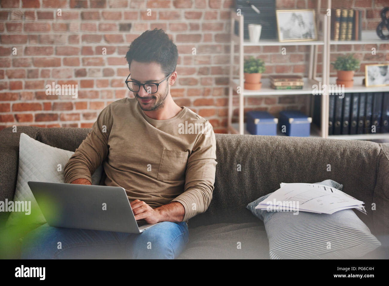 Homme assis sur la table à la maison à l'aide d'ordinateur portable Banque D'Images
