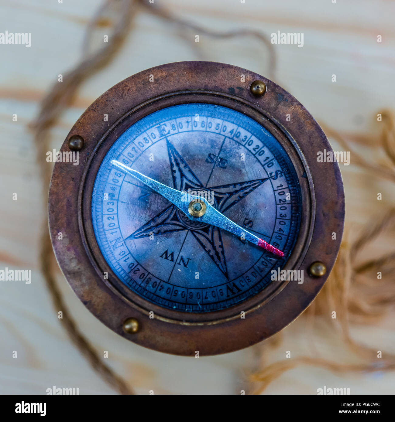 Compas nautique ancienne vue de dessus fait de métal et de verre se dresse sur une surface en bois. Une corde autour d'une boussole. Direction et d'orientation. Droit Banque D'Images