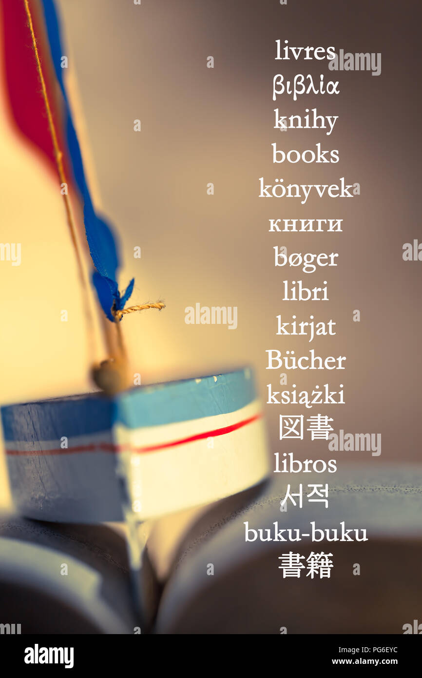 Le mot 'Livres' écrit en différentes langues à l'image d'arrière-plan avec toy voilier entre la pages de livre ouvert Banque D'Images