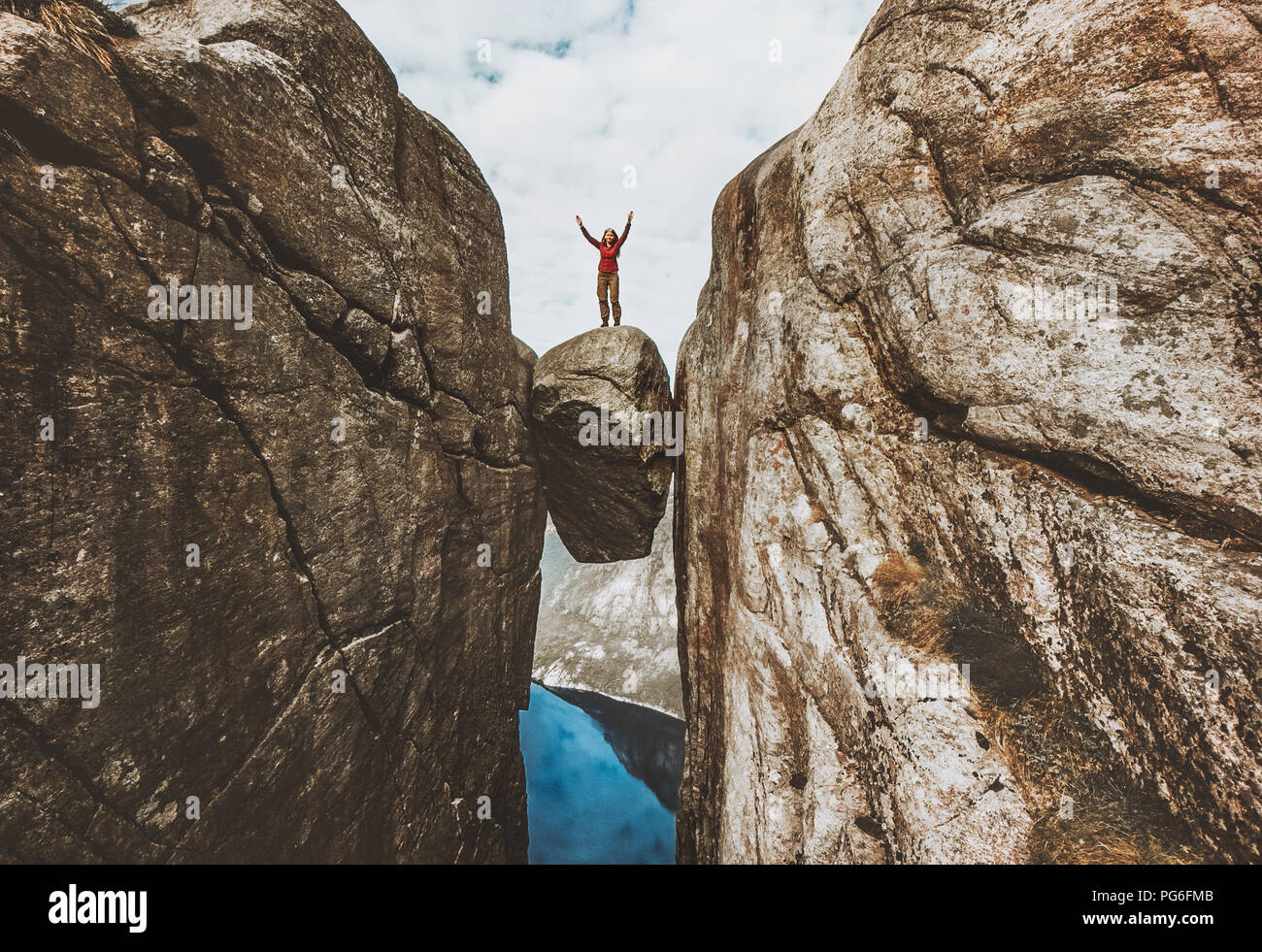 Brave woman traveler debout sur Kjeragbolten soulevées mains voyageant en Norvège Kjerag montagne vacances d'aventure concept Réussite Banque D'Images