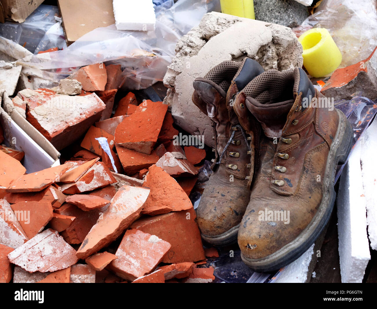 Ancienne paire de bottes des travailleurs jetés dans une thats presque plein constructeurs passer à l'extérieur de l'emplacement de l'édifice Banque D'Images