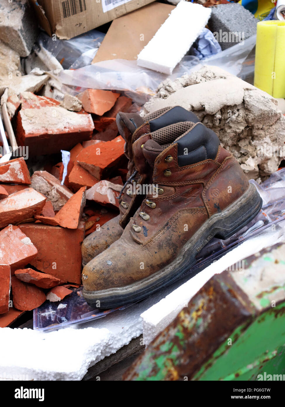 Ancienne paire de bottes des travailleurs jetés dans une thats presque plein constructeurs passer à l'extérieur de l'emplacement de l'édifice Banque D'Images