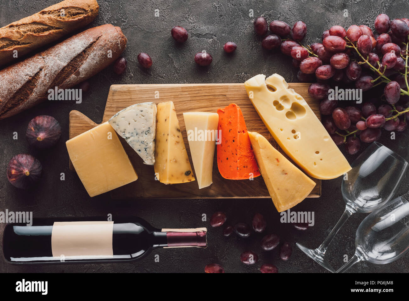 Mise à plat avec des baguettes, assortiment de fromage, bouteille de vin et des fruits sur la table sombre Banque D'Images