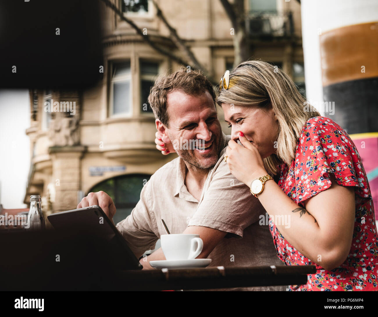 Couple heureux avec comprimé à un café en plein air Banque D'Images