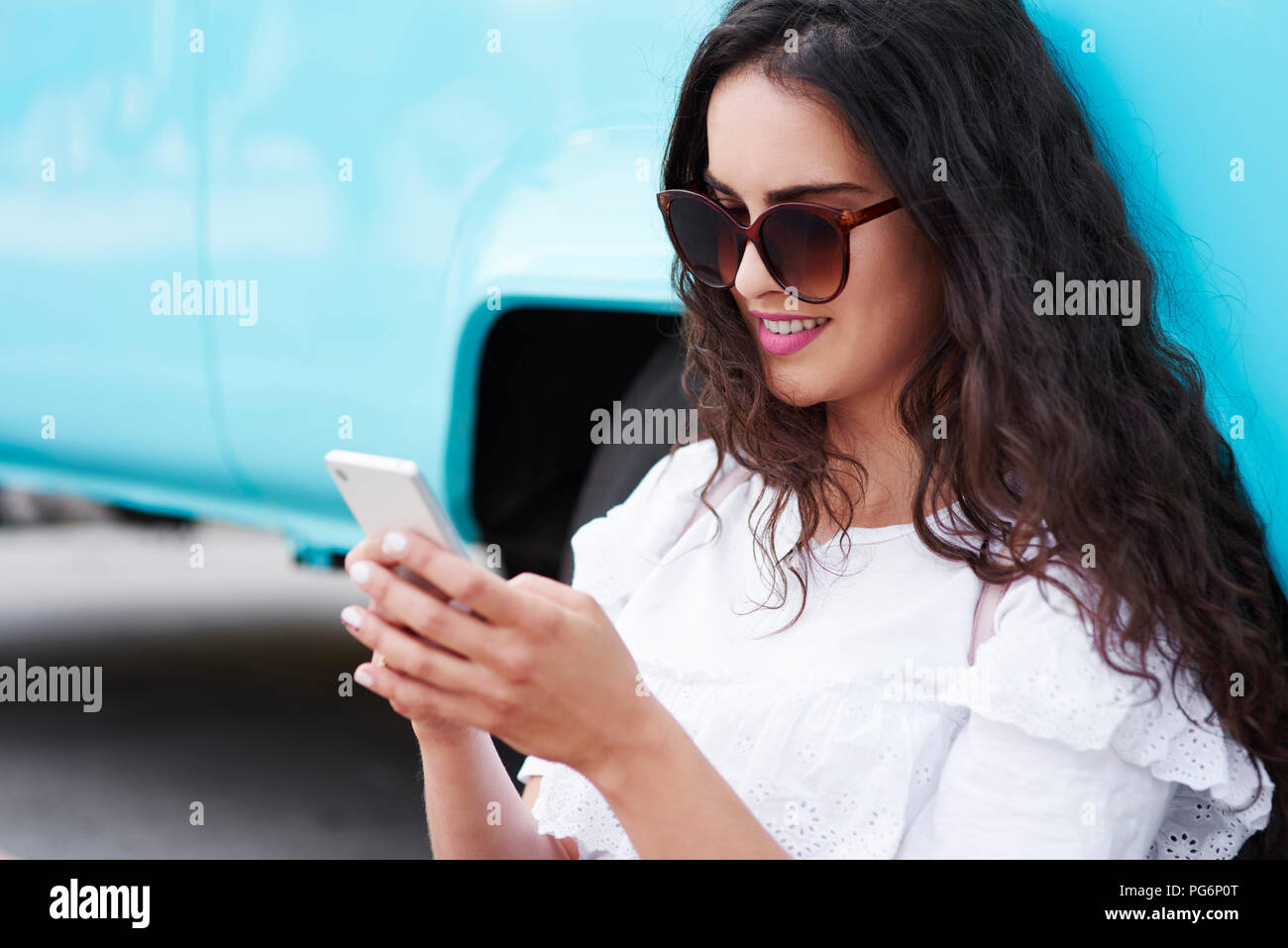 Smiling young woman using cell phone outdoors Banque D'Images
