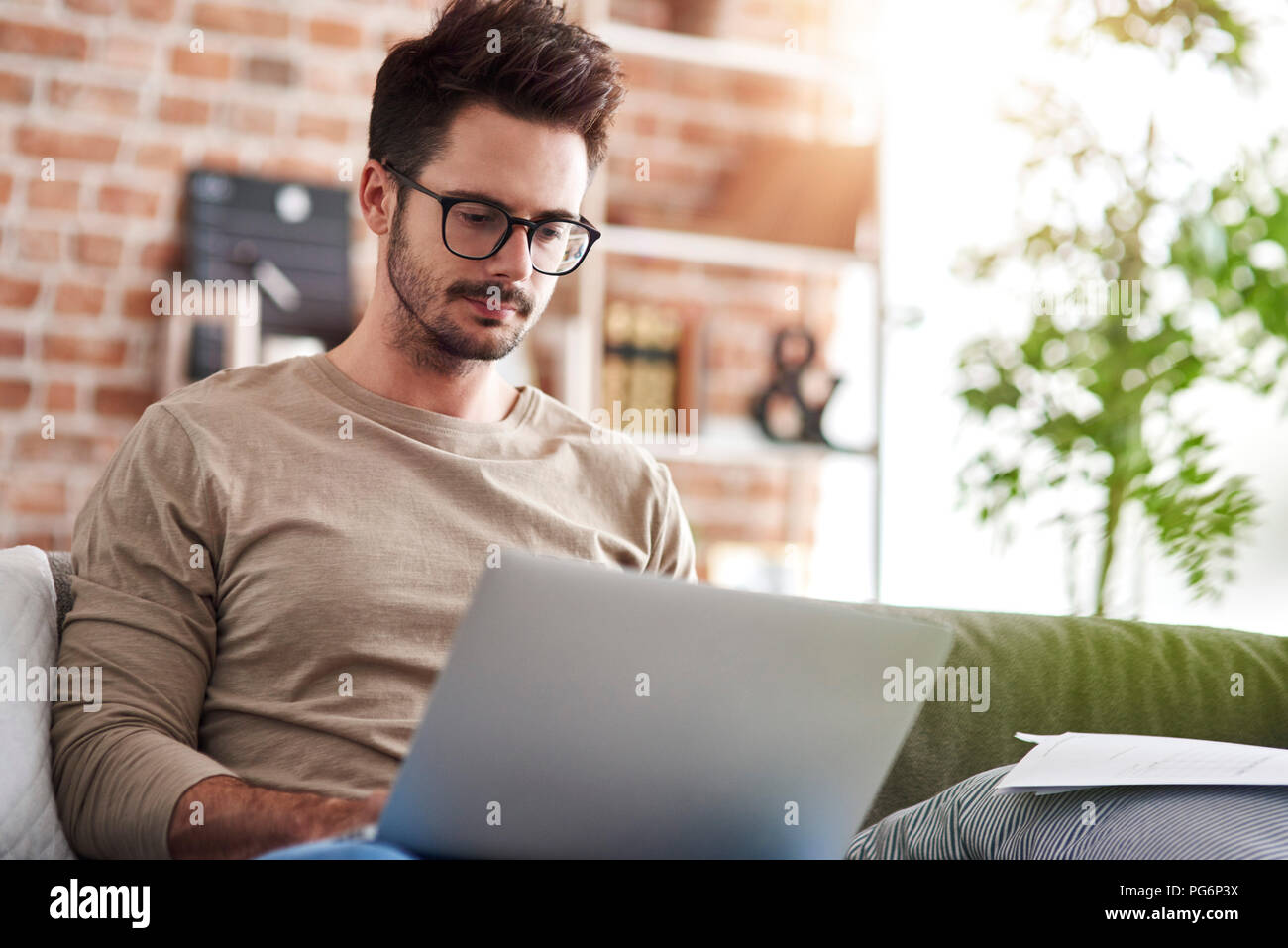 Portrait de l'homme assis sur la table à la maison à l'aide d'ordinateur portable Banque D'Images