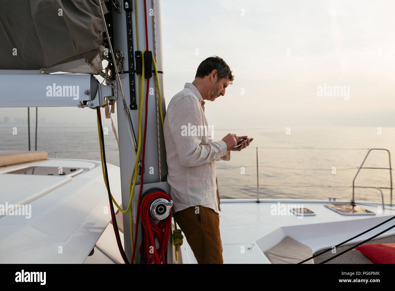 Homme Marure sur catamaran, using smartphone Banque D'Images