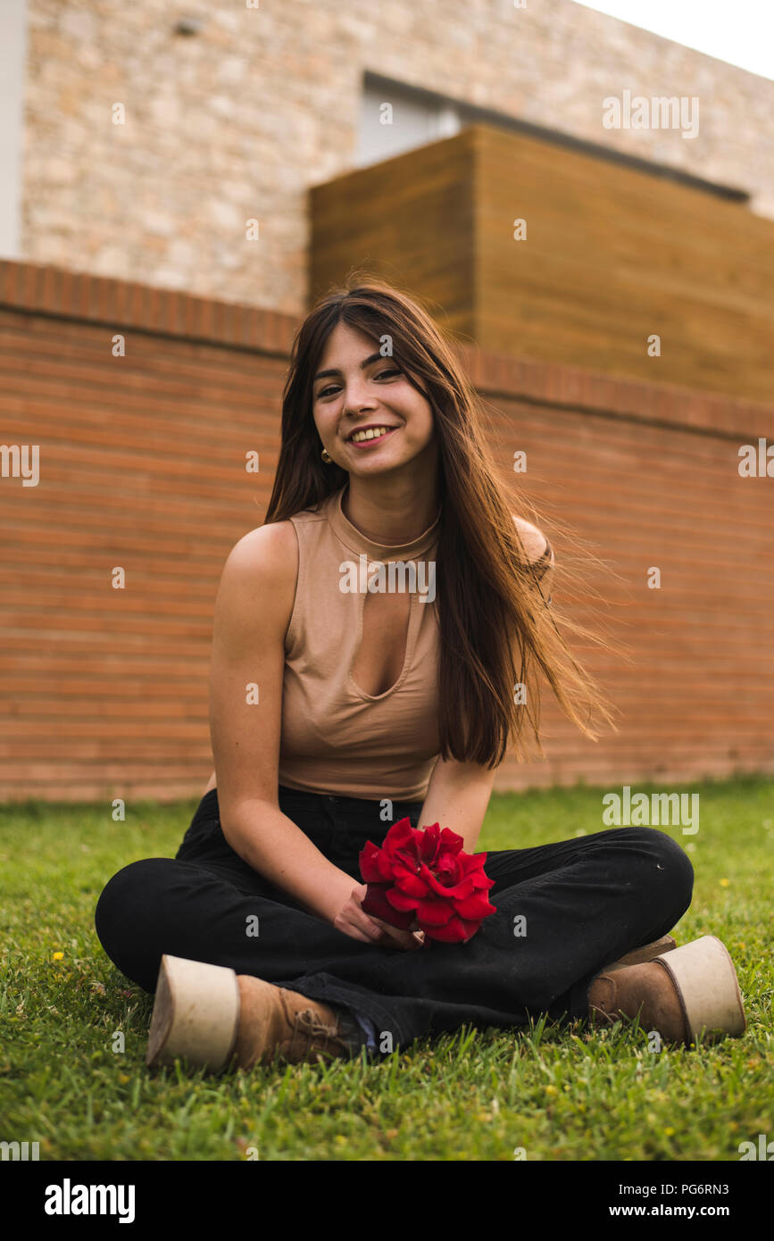 Portrait de jeune femme à la rose assis sur la pelouse Banque D'Images