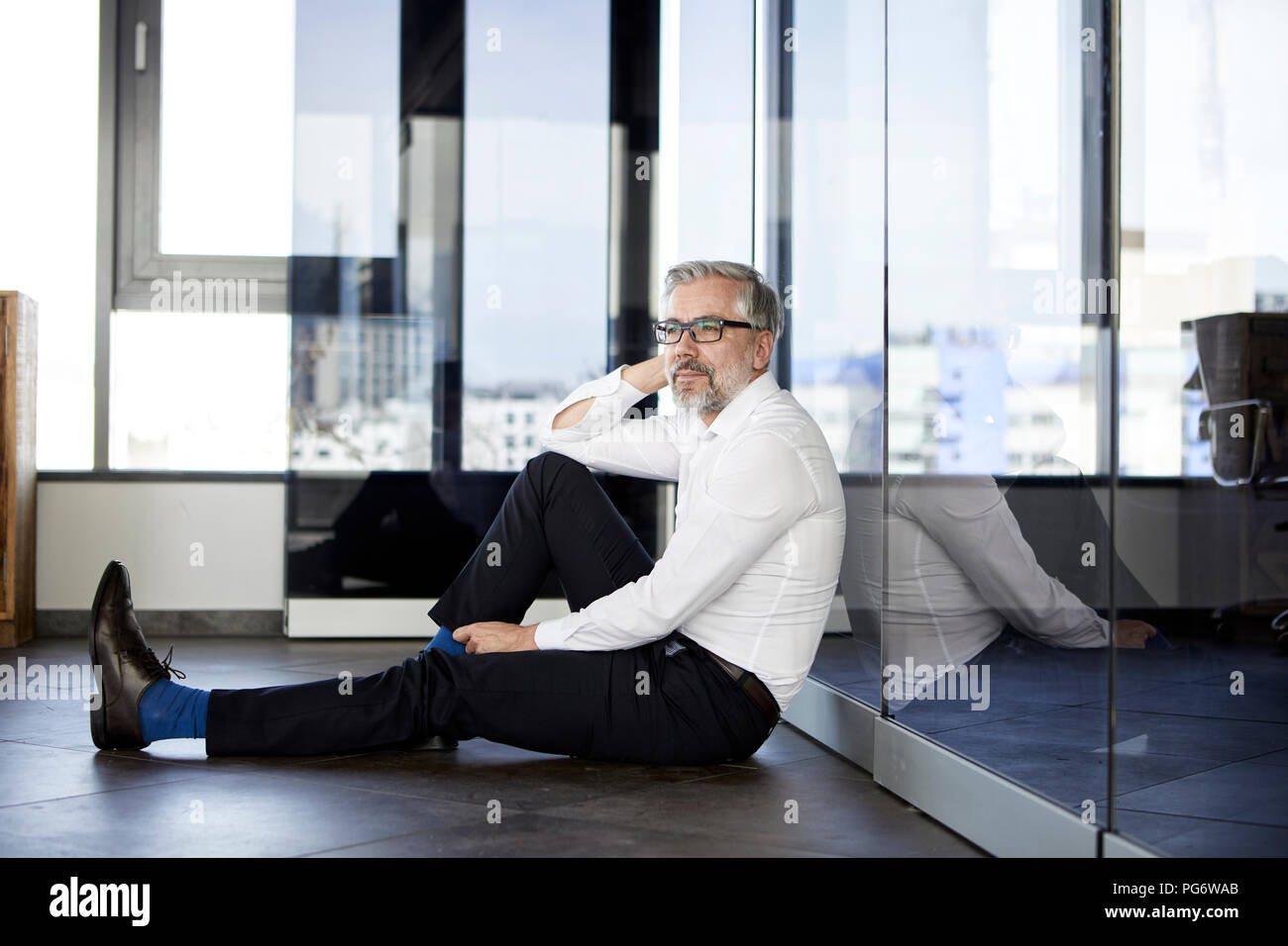 Businessman sitting on the floor in office Banque D'Images