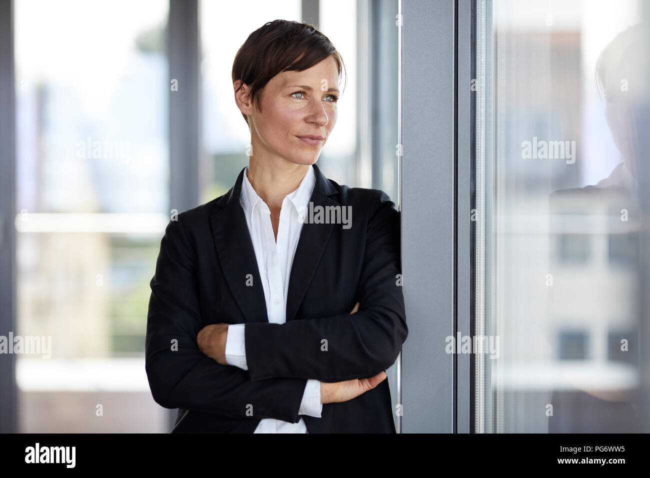 Businesswoman in office looking out of window Banque D'Images