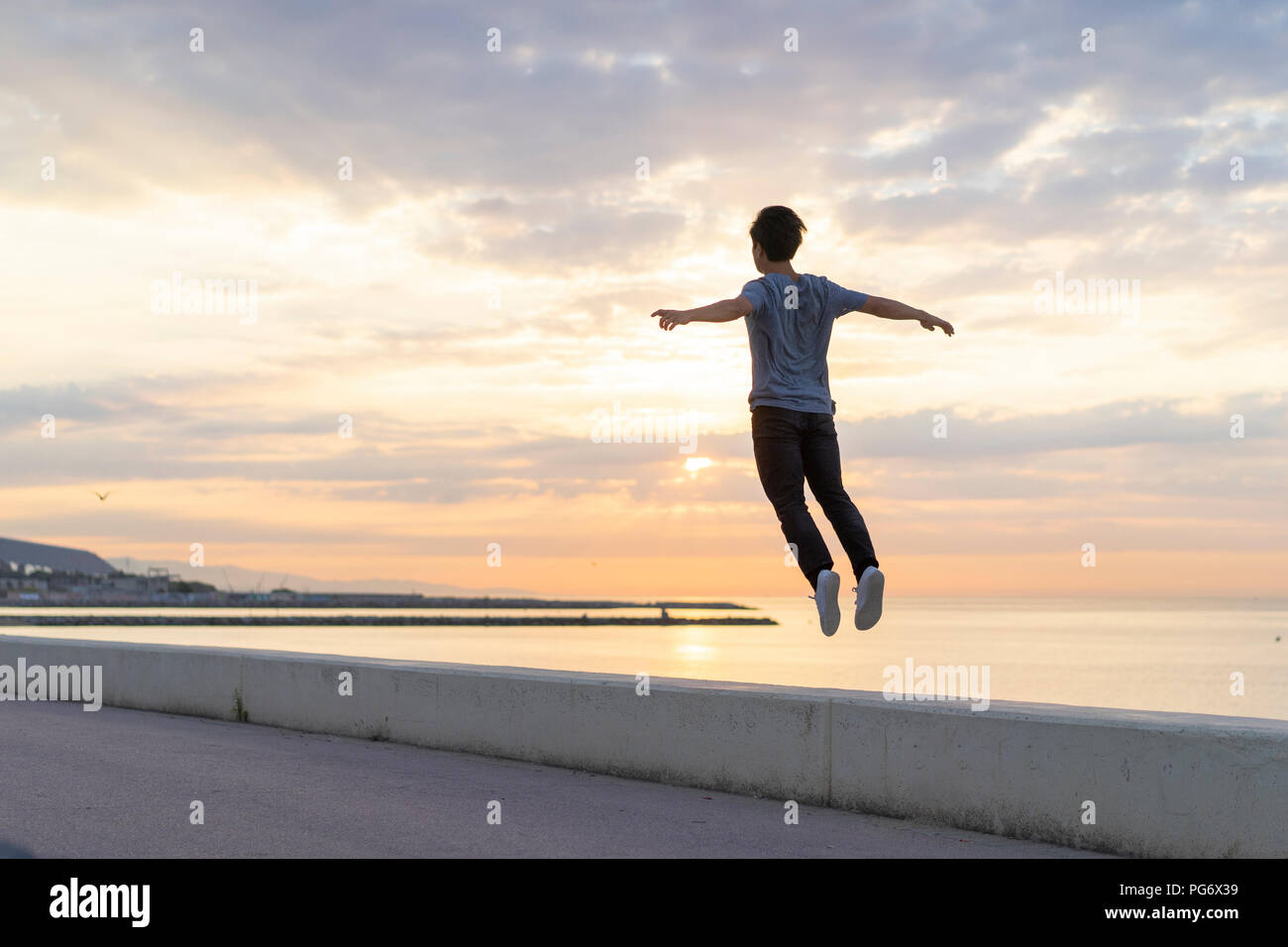 Les jeunes Chinois sauter sur mur à la plage Banque D'Images