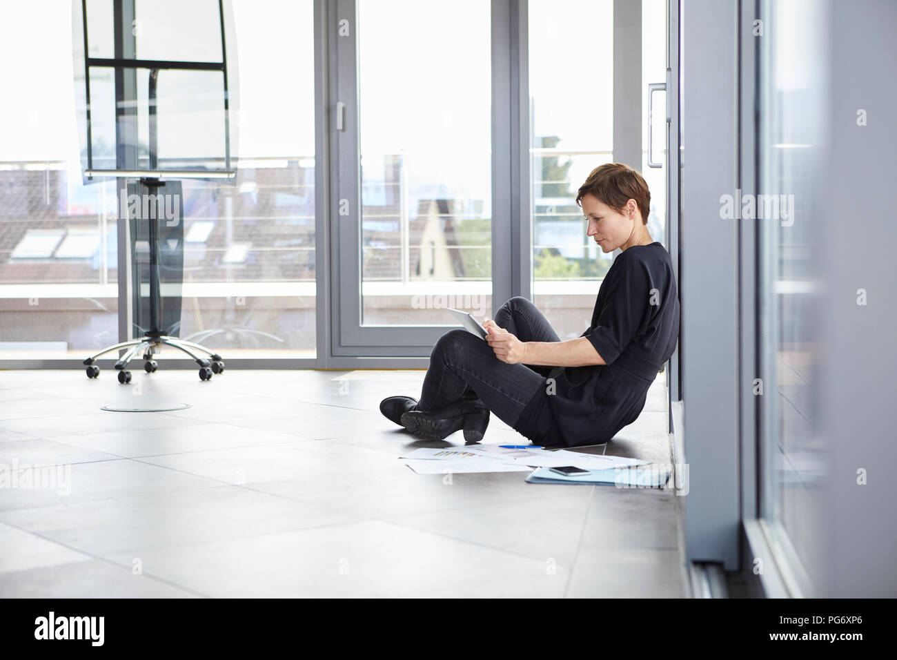 Businesswoman assis sur le plancher d'office à l'aide de tablet Banque D'Images