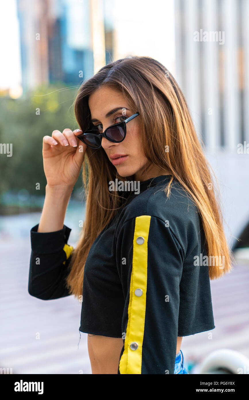 Portrait of attractive young woman wearing sunglasses dans la ville Banque D'Images