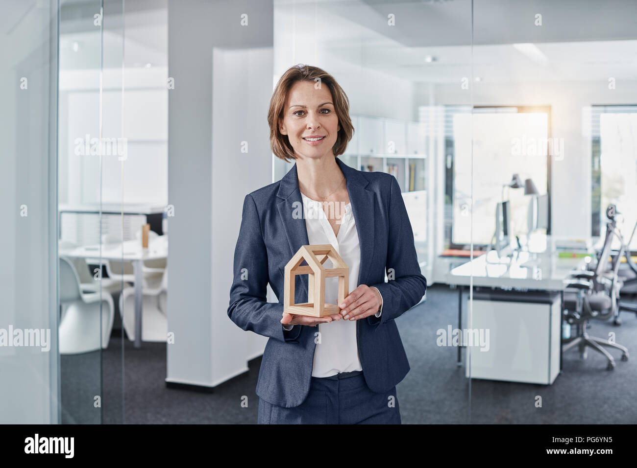 Portrait of smiling businesswoman holding architectural model in office Banque D'Images