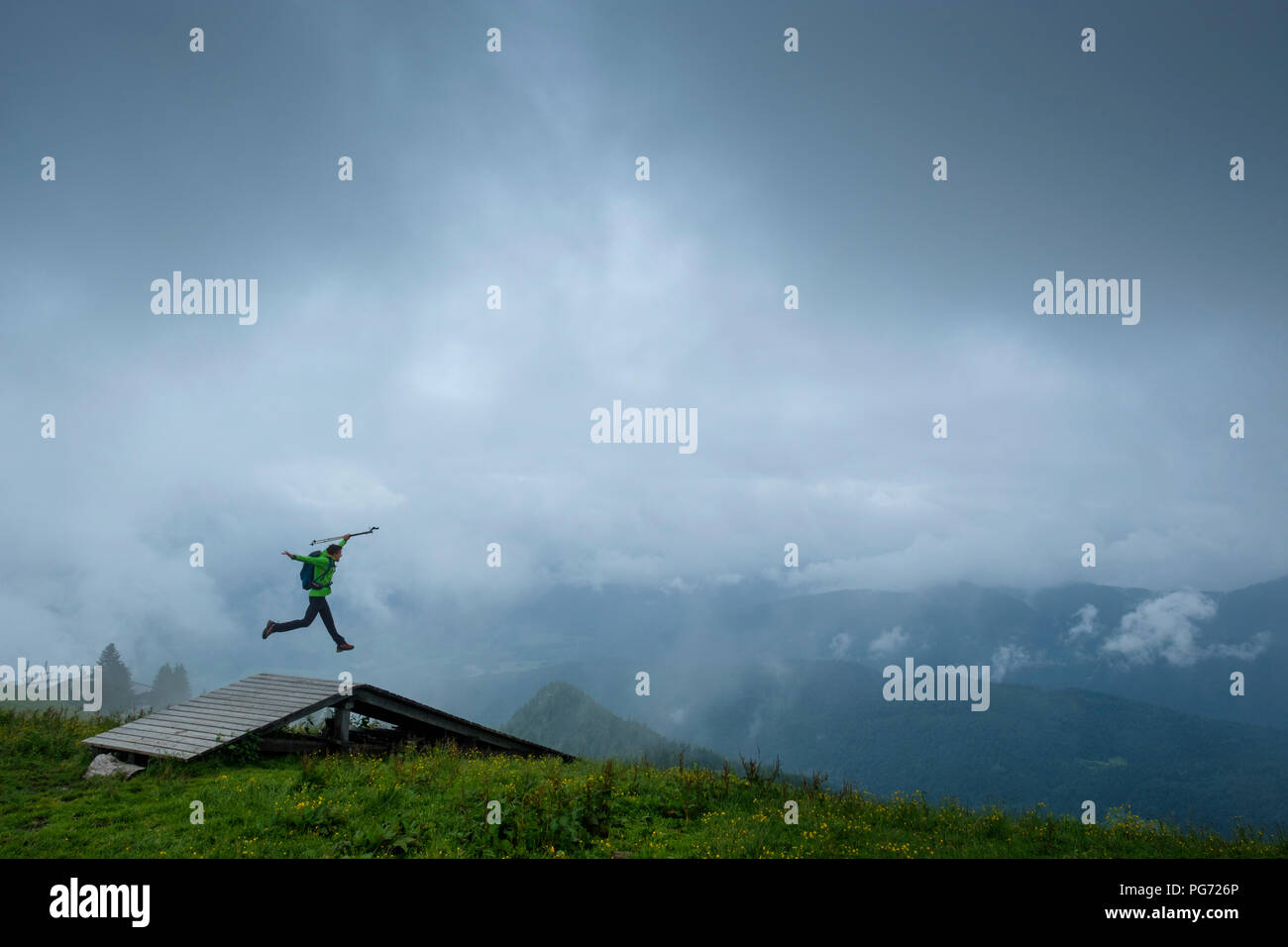 Allemagne, Brauneck, jeune randonneur avec des bâtons de marche sac à dos et de sauter dans l'air Banque D'Images