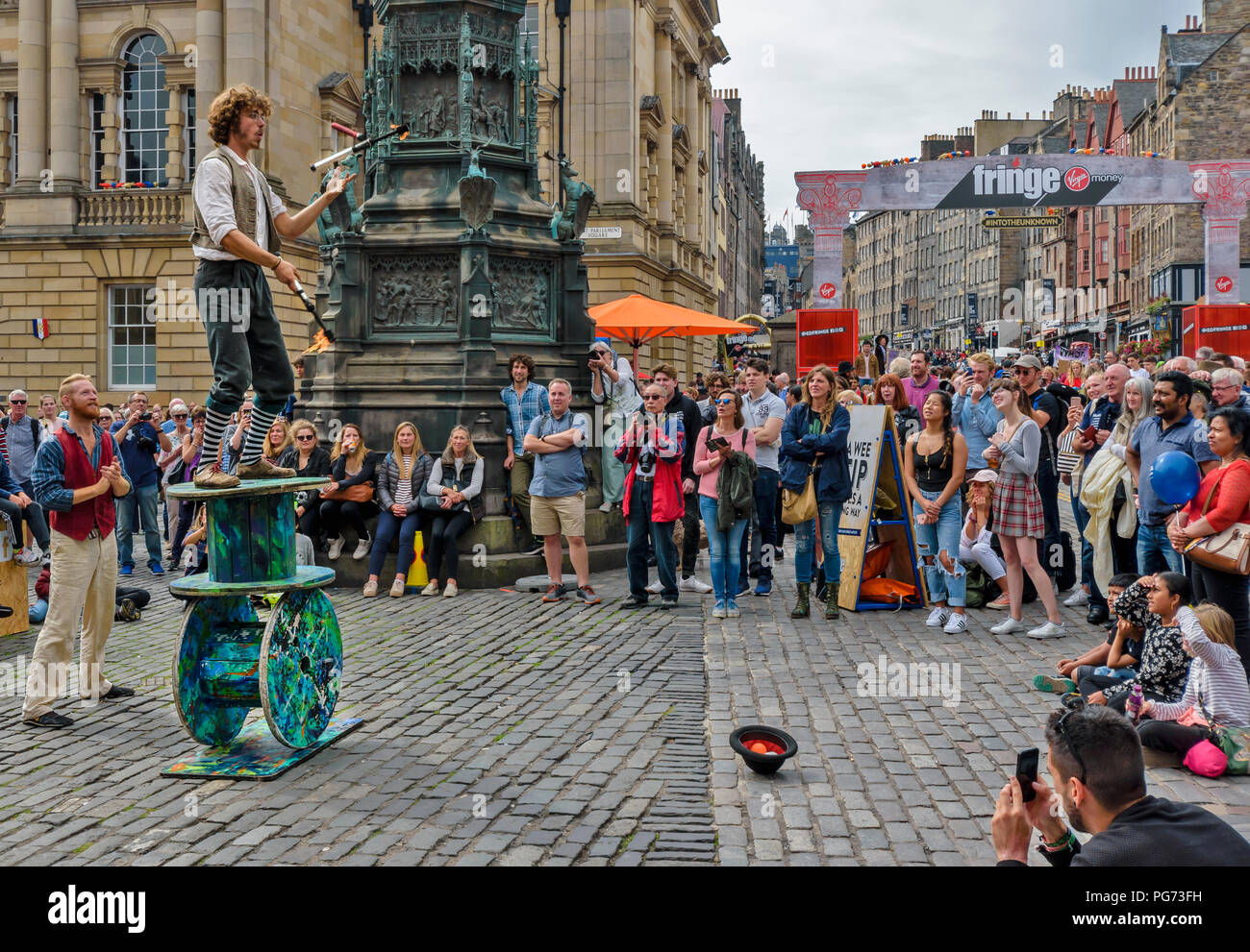 EDINBURGH FESTIVAL FRINGE 2018 Un jongleur avec des flammes et une lame en équilibre sur de grandes bobines en bois Banque D'Images