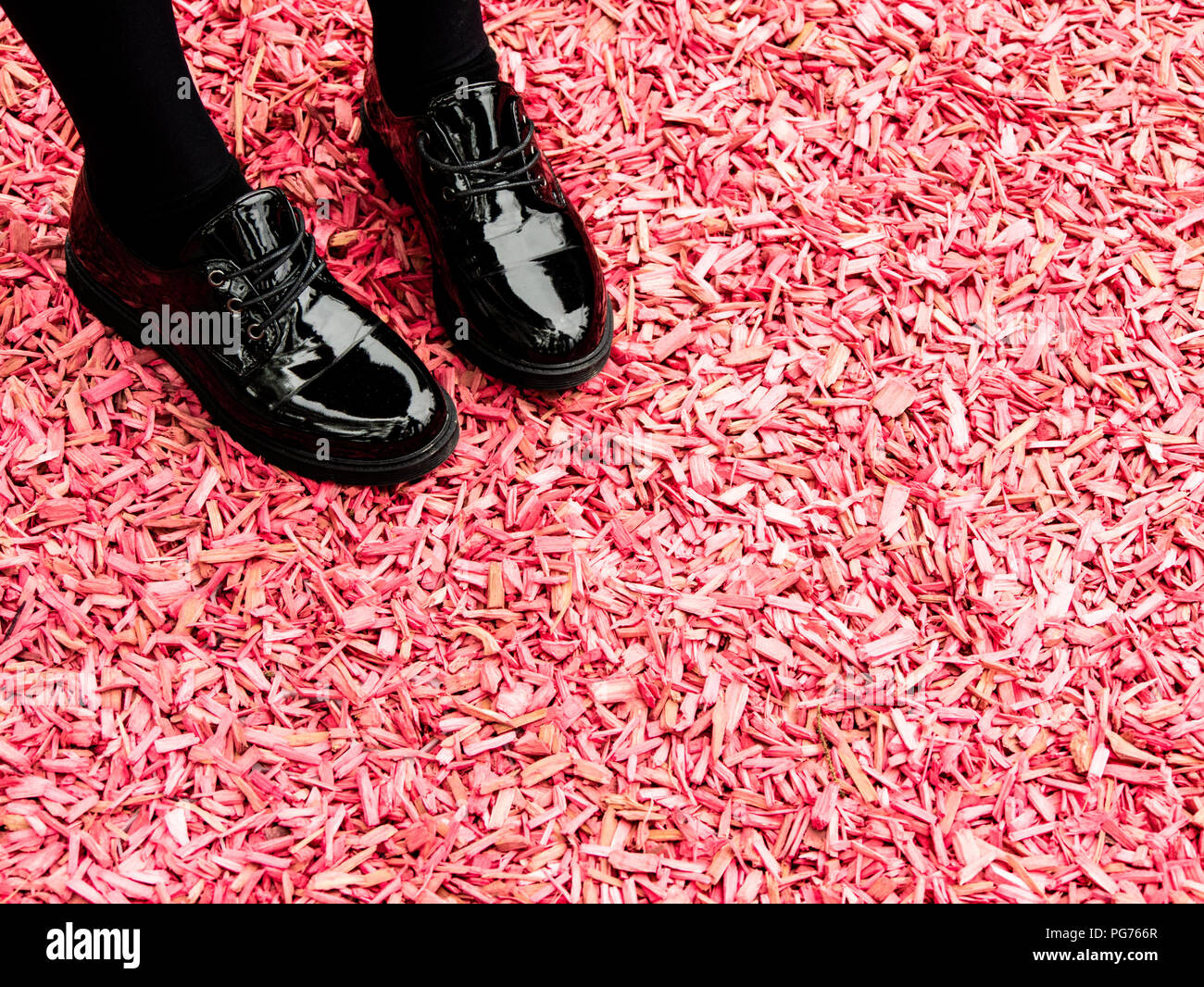 Chaussures noires brillantes de la jeune fille rose sur la masse de copeaux Banque D'Images