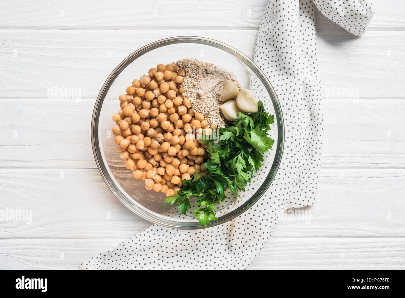Vue de dessus les pois chiches, le persil et épices Ingrédients pour l'hoummos à Bol sur surface en bois Banque D'Images