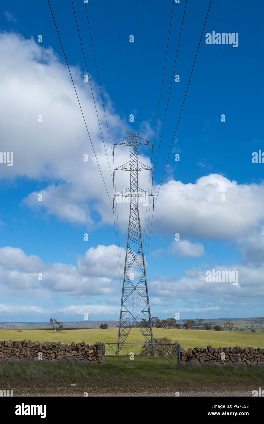 Les lignes de transport d'électricité aléatoire et grande tour situé sur les terres rurales, derrière un mur de pierre et metal gate. Situé au nord d'Adélaïde. Banque D'Images