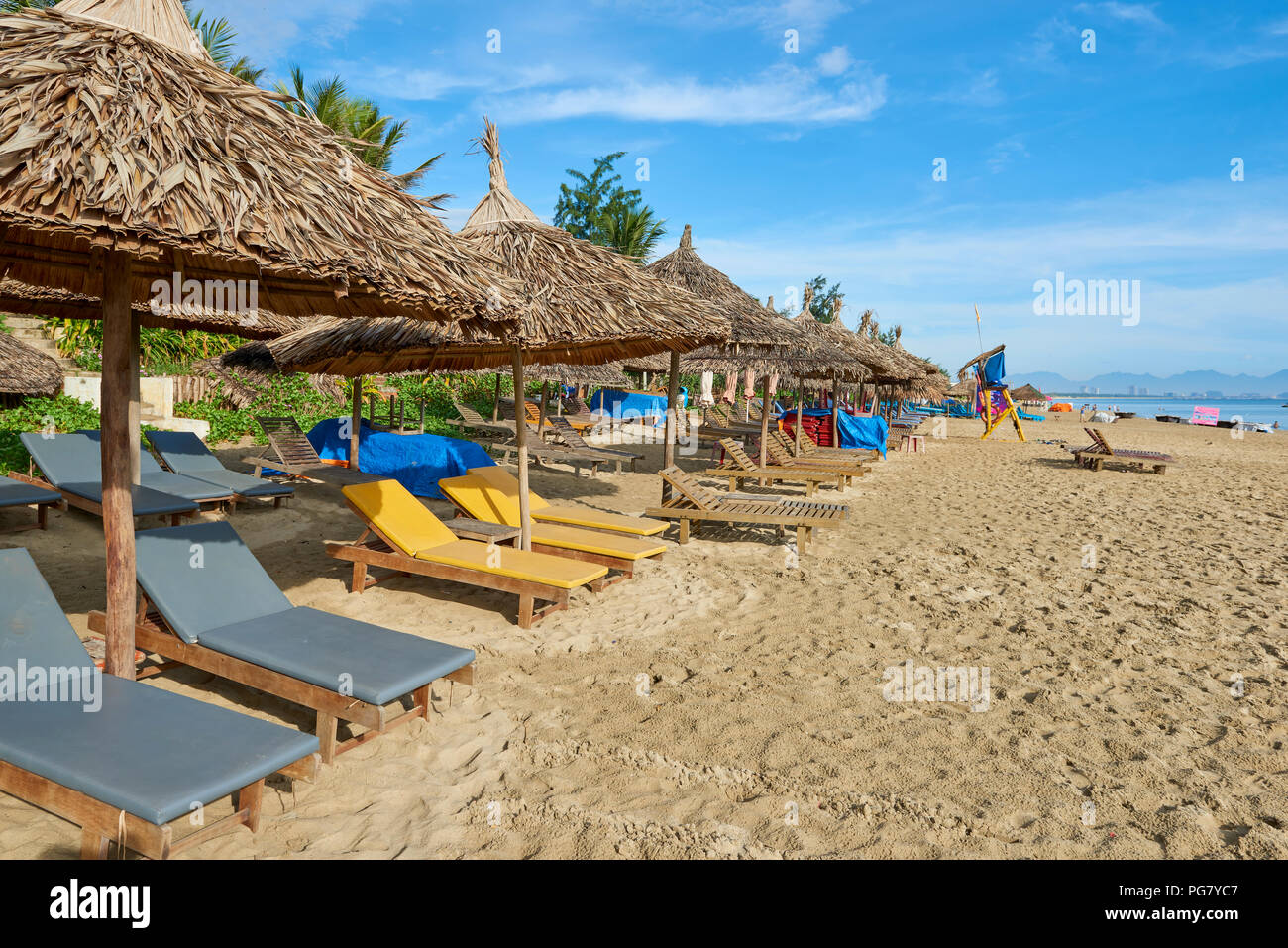 Chaises longues sous des parasols de paille sur le sable de la plage de An Bang, dans le centre du Vietnam. La ville côtière est situé près de la ville de Hoi An, protégée par l'UNESCO Banque D'Images