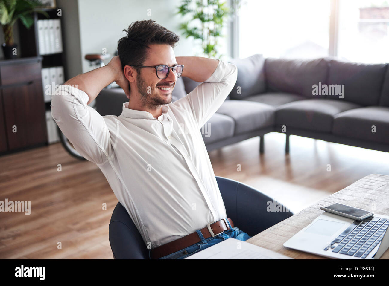 Content businessman sitting at desk at home office Banque D'Images