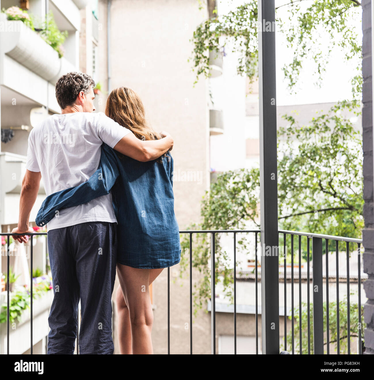 Vue arrière du couple dans des chemises de nuit debout sur balcon hugging Banque D'Images