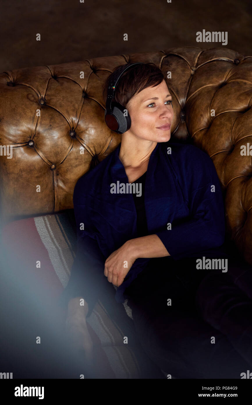 Femme avec casque allongé sur un canapé, écouter de la musique Banque D'Images