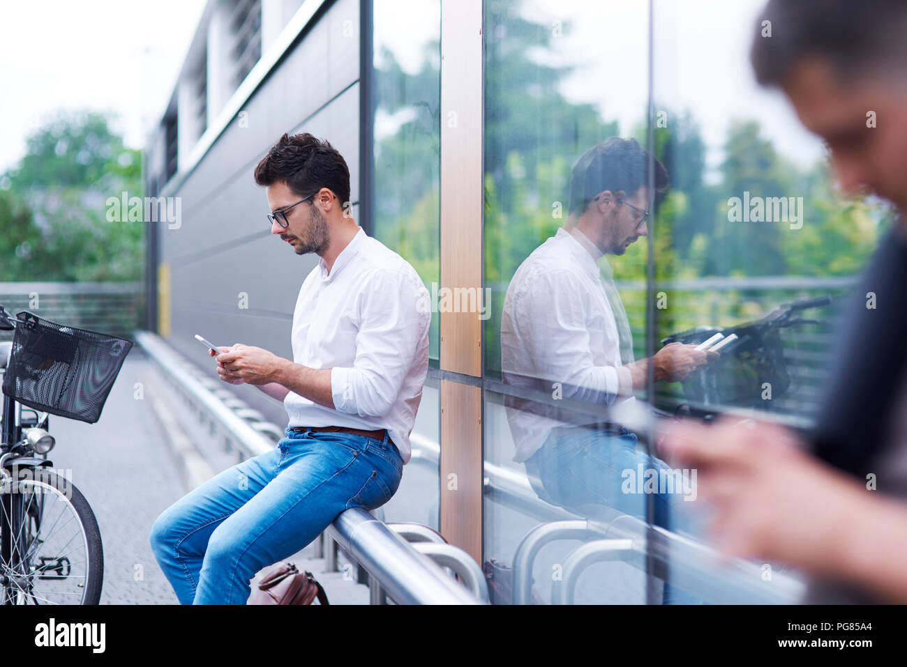 Businessman with bicycle using cell phone outdoors Banque D'Images