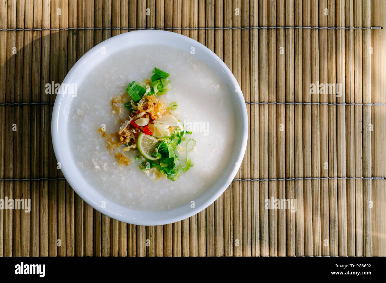 De style thaïlandais ou gruau de riz Riz congee avec ingrédient actif de condiments. (Sauce de poisson, l'ail frit,poivre,piment, oignon de printemps, coriandre et citron vert). Banque D'Images