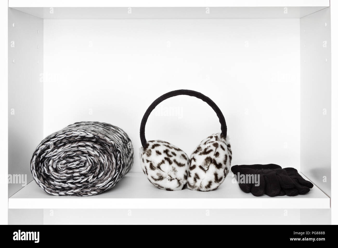 Vêtements femme accessoires. Écharpe tricotée torsadée, la fausse fourrure cache-oreilles d'hiver, des gants de laine noir sur blanc à l'intérieur du plateau technique. Copy space Banque D'Images