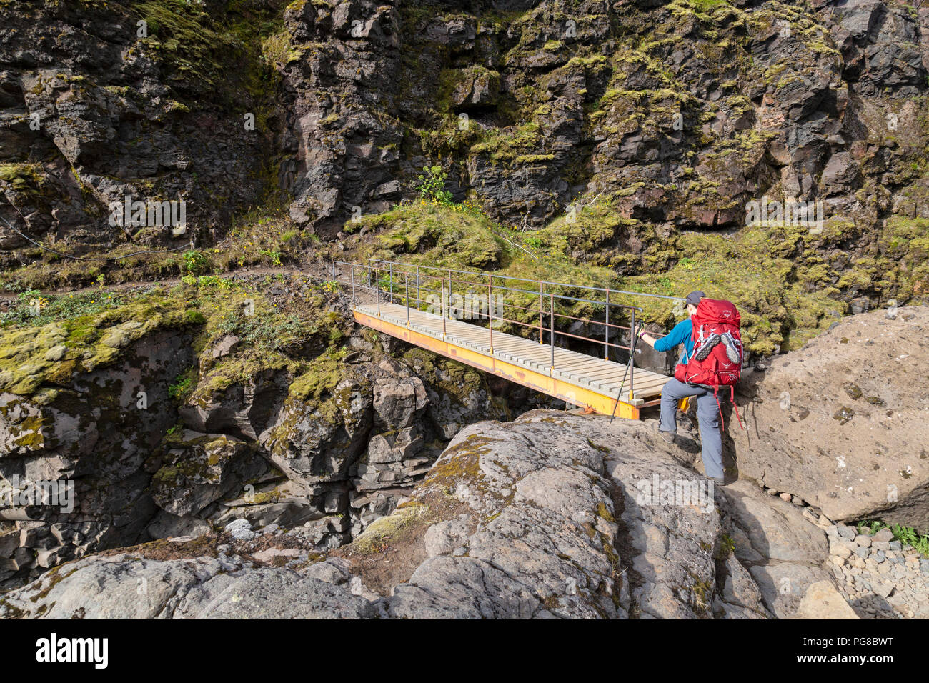 Une seule femme randonneur traversant un pont sur le sentier Laugavegur en Islande. Banque D'Images