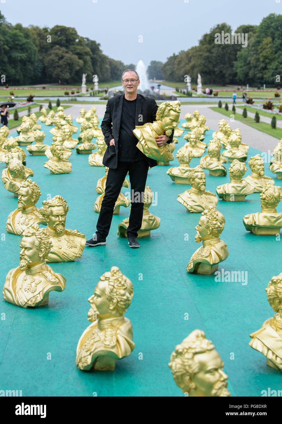 Munich, Allemagne. Août 24, 2018. L'artiste Ottmar Hörl de Nuremberg se penche sur l'appareil photo dans le Palais Nymphenburg Park aux côtés de son installation artistique en l'honneur du conte de fées le roi Ludwig II. 100 images de Louis II ont été mis en place dans le contexte de l'art un jour avant l'installation du 173e anniversaire de Ludwig. Credit : Matthias Balk/dpa/Alamy Live News Banque D'Images