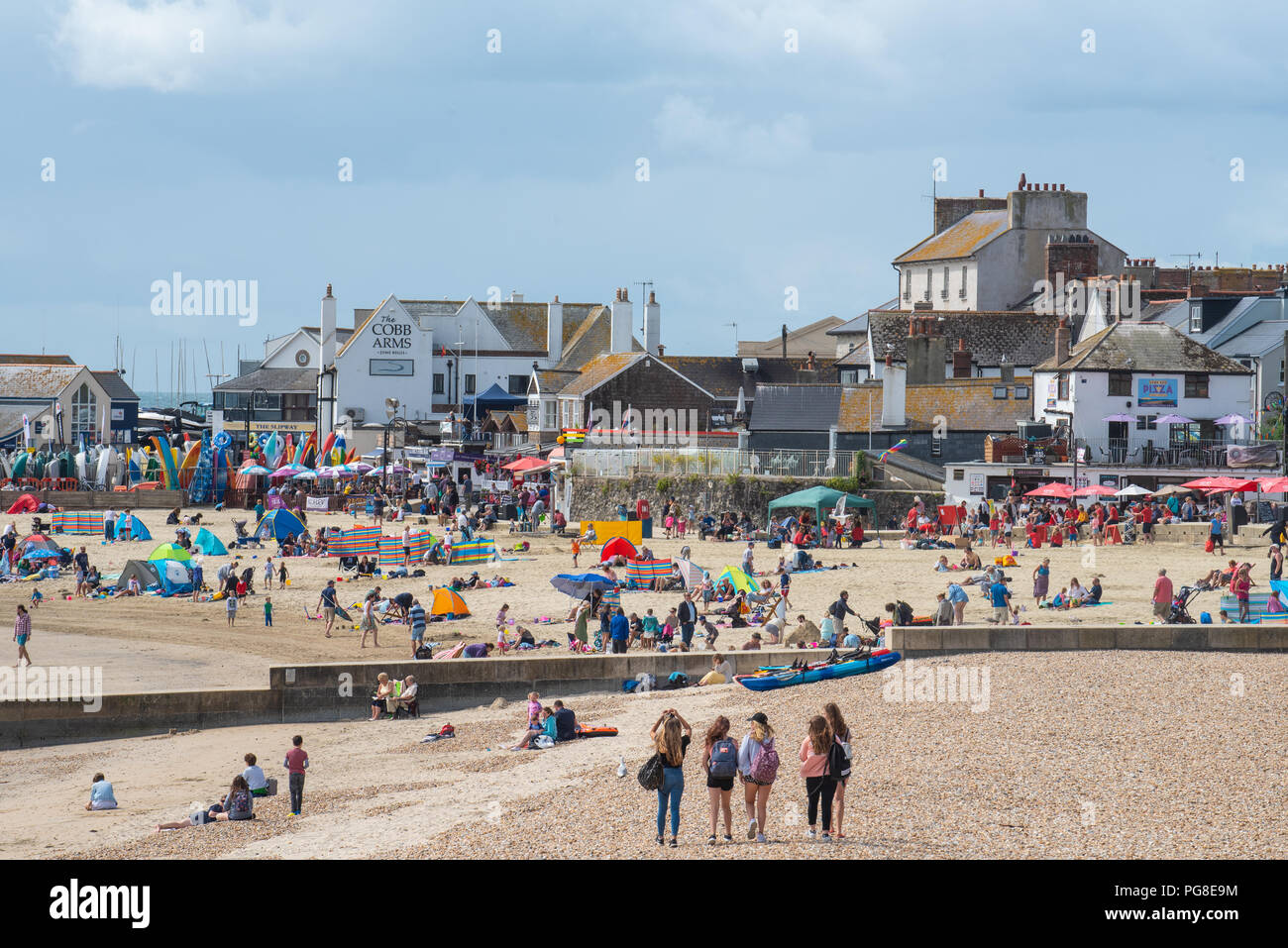 Lyme Regis, dans le Dorset, UK. 24 août 2018. Météo France : Les visiteurs profitent des éclaircies et un vent frais sur la plage à Lyme Regis au début de la Banque week-end de vacances. Refroidisseur, on prévoit que les conditions plus nuageux avec quelques averses, les éclosions. Credit : Celia McMahon/Alamy Live News Banque D'Images