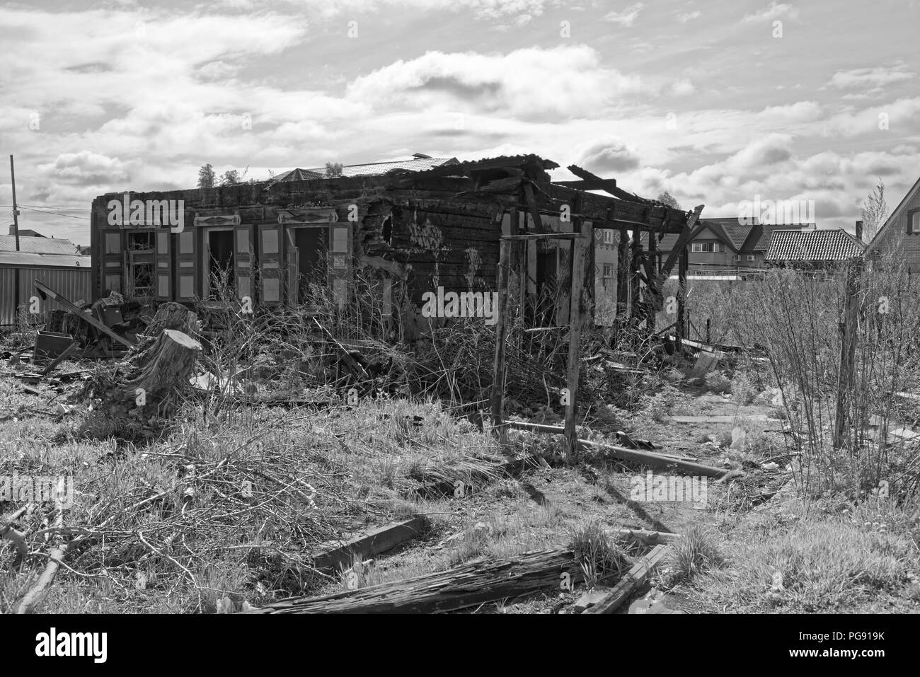 Vieille maison brûlée contre ciel nuageux comme image en noir et blanc. Komsomolsk-sur-Amure, Russie Banque D'Images