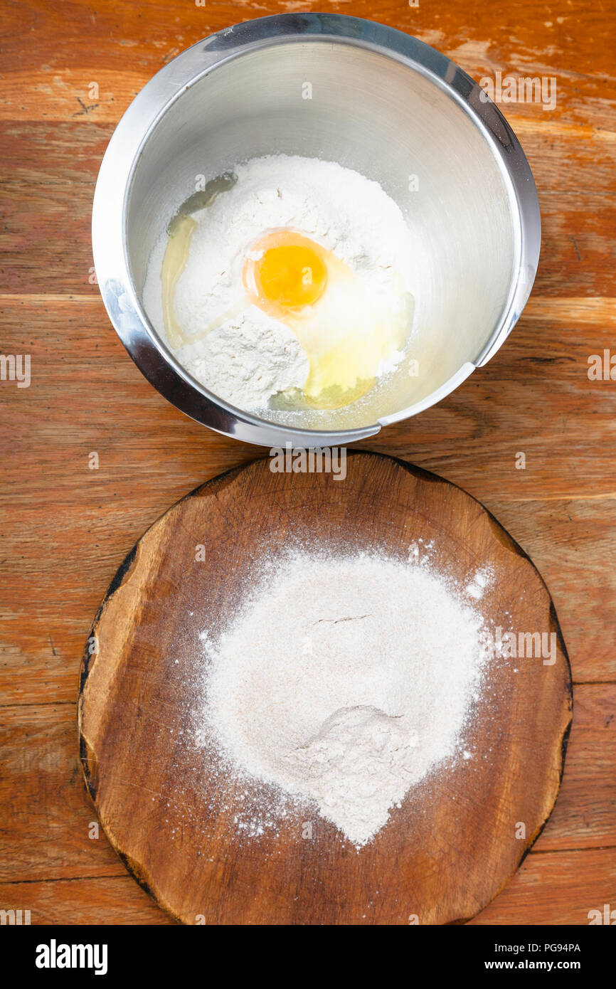 La cuisson de la tarte - tas de farine à bord et la farine avec les oeufs cassés dans un bol en acier Banque D'Images