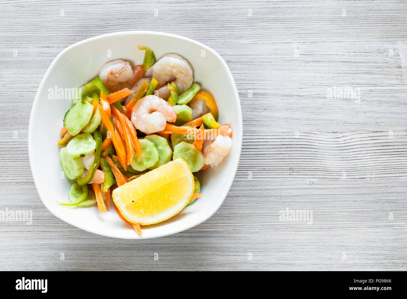 La cuisine indienne - salade de langoustines à partir de légumes de saison et les crevettes dans un bol blanc sur planche en bois gris avec copyspace Banque D'Images