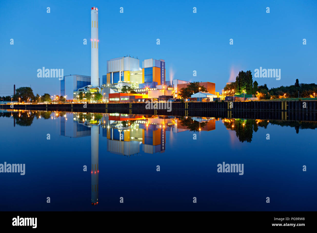 Une usine d'incinération à un canal à heure bleue dans la nuit. Des couleurs fortes et très clairement la réflexion. Banque D'Images