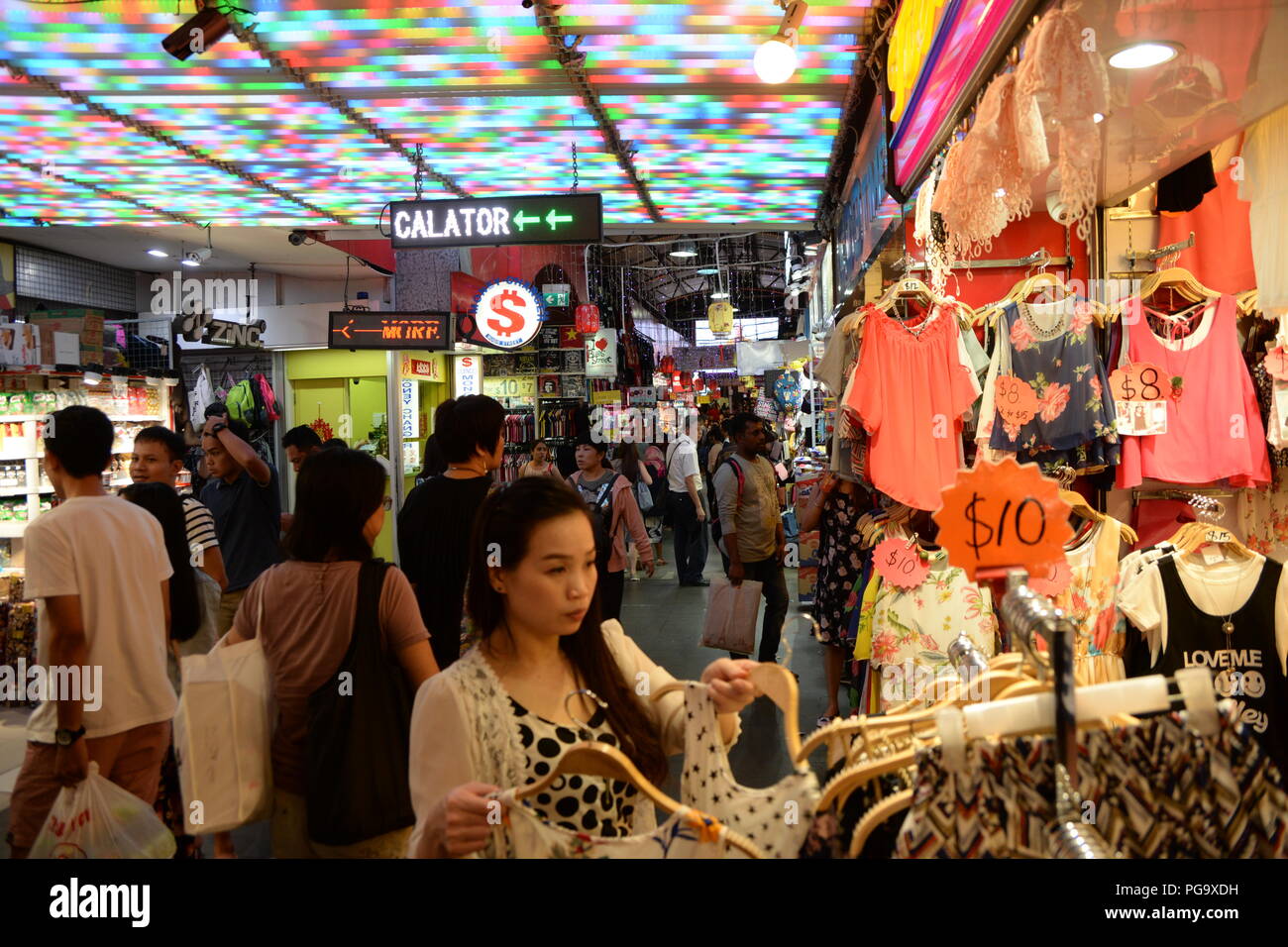Une femme boutiques pour une robe sur le marché. Populaire avec les habitants et les touristes, Bugis Street Market est bien connu pour être l'un des endroits les moins chers à Singapour pour acheter des souvenirs, d'accessoires, vêtements, appareils électroniques, articles ménagers et des produits cosmétiques. Banque D'Images