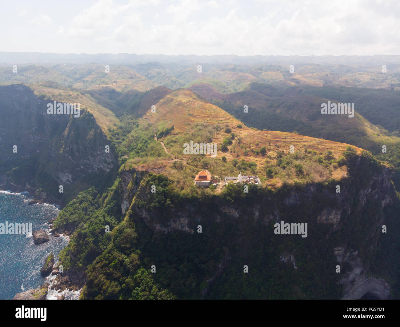 Vue aérienne d'un temple à côté d'une falaise avec une grande forêt vert jaune à l'horizon Banque D'Images