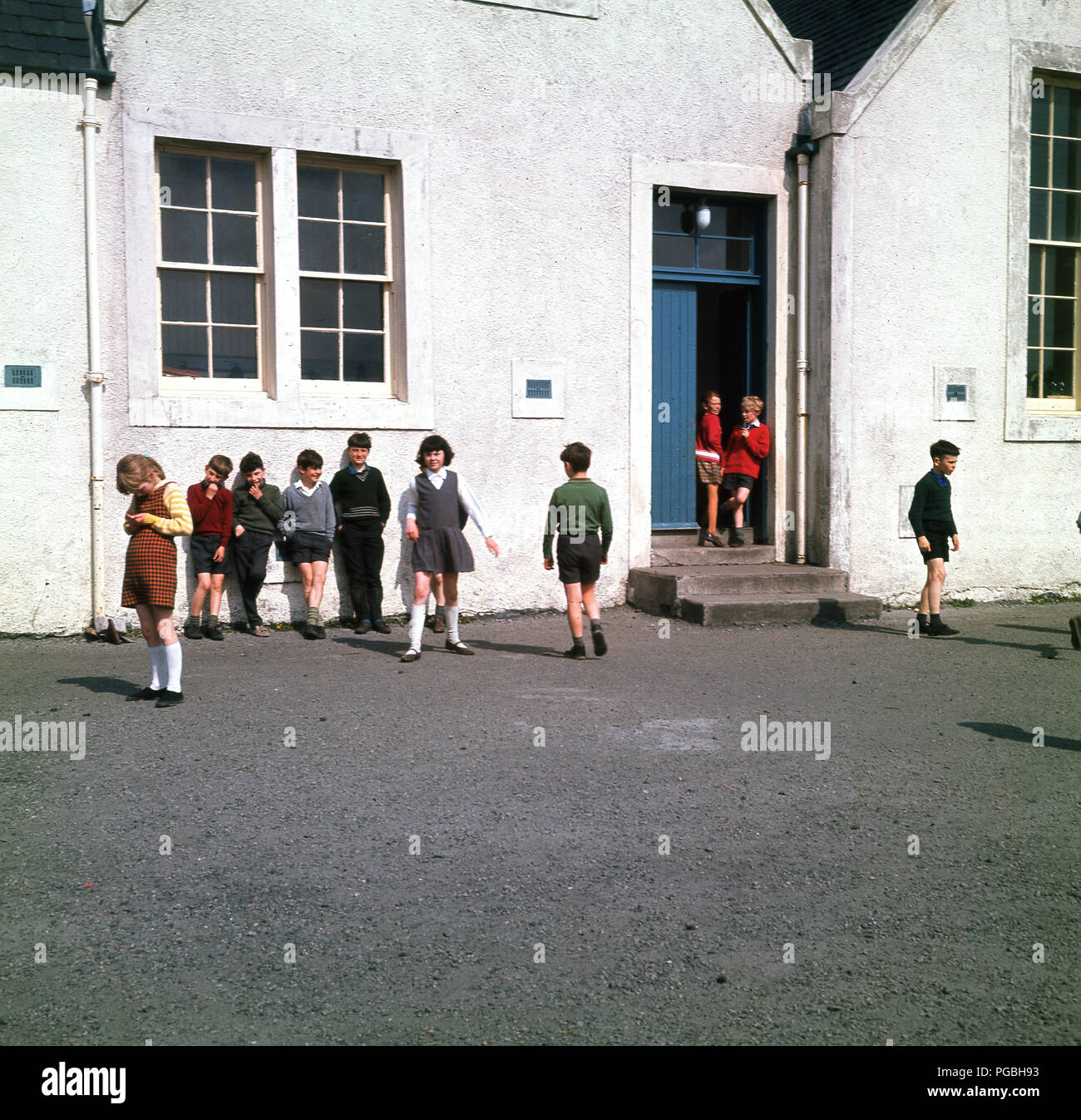 Des années 1960, les enfants à l'extérieur de l'école, dans l'aire de jeux, à Lochboisdale, sur l'île de South Uist, dans les Hébrides extérieures, en Écosse. Banque D'Images