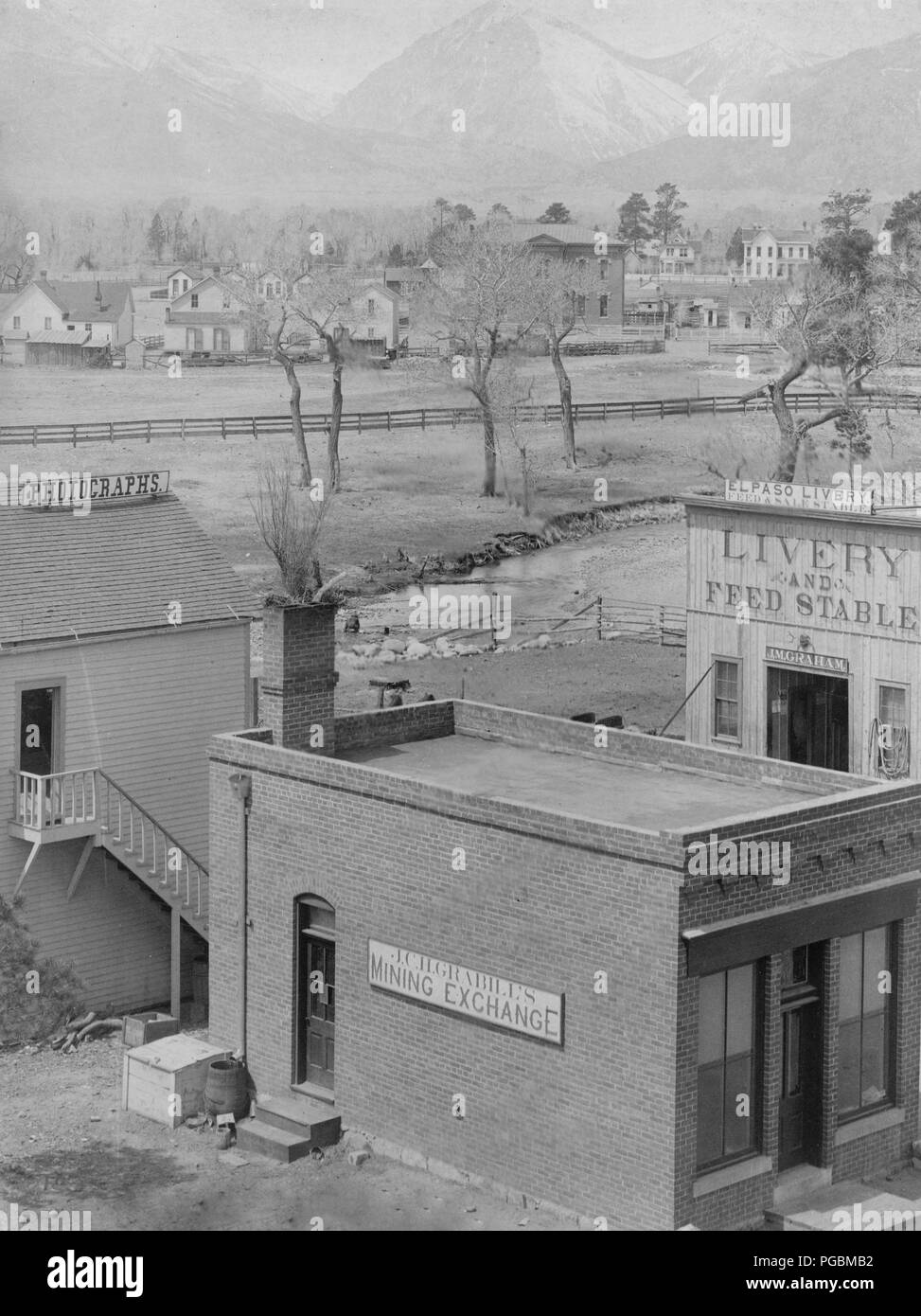 La photographie montre trois bâtiments avec des signes lecture : l'exploitation minière Grabill change, des photographies, et El Paso Livery ; river et maisons en milieu-sol, montagnes en arrière-plan. Banque D'Images