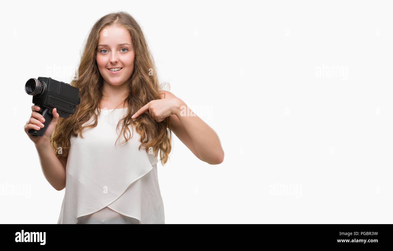 Jeune blond woman holding super 8 caméra vidéo avec surprise face à face à lui-même Banque D'Images