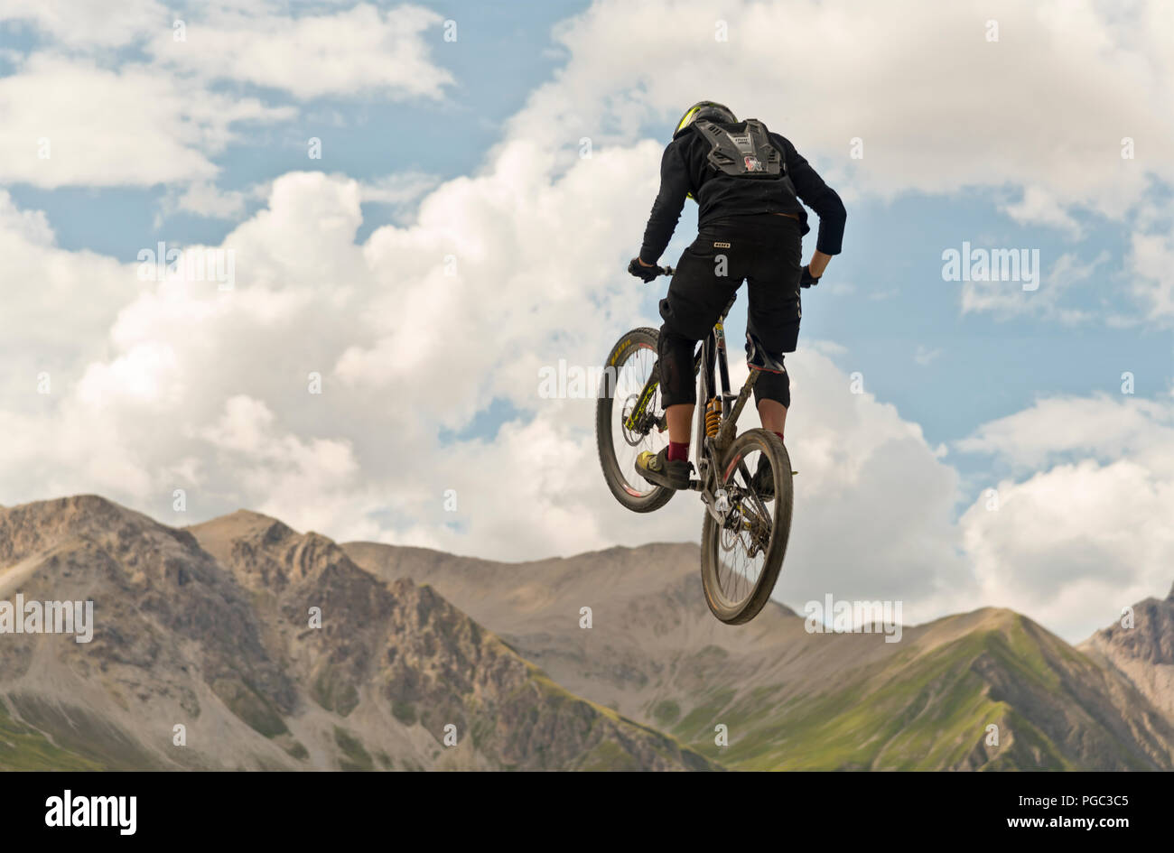 L'homme d'effectuer une location stunt dans l'air sur un fond de sommets de montagnes alpines et un ciel nuageux ciel bleu Banque D'Images