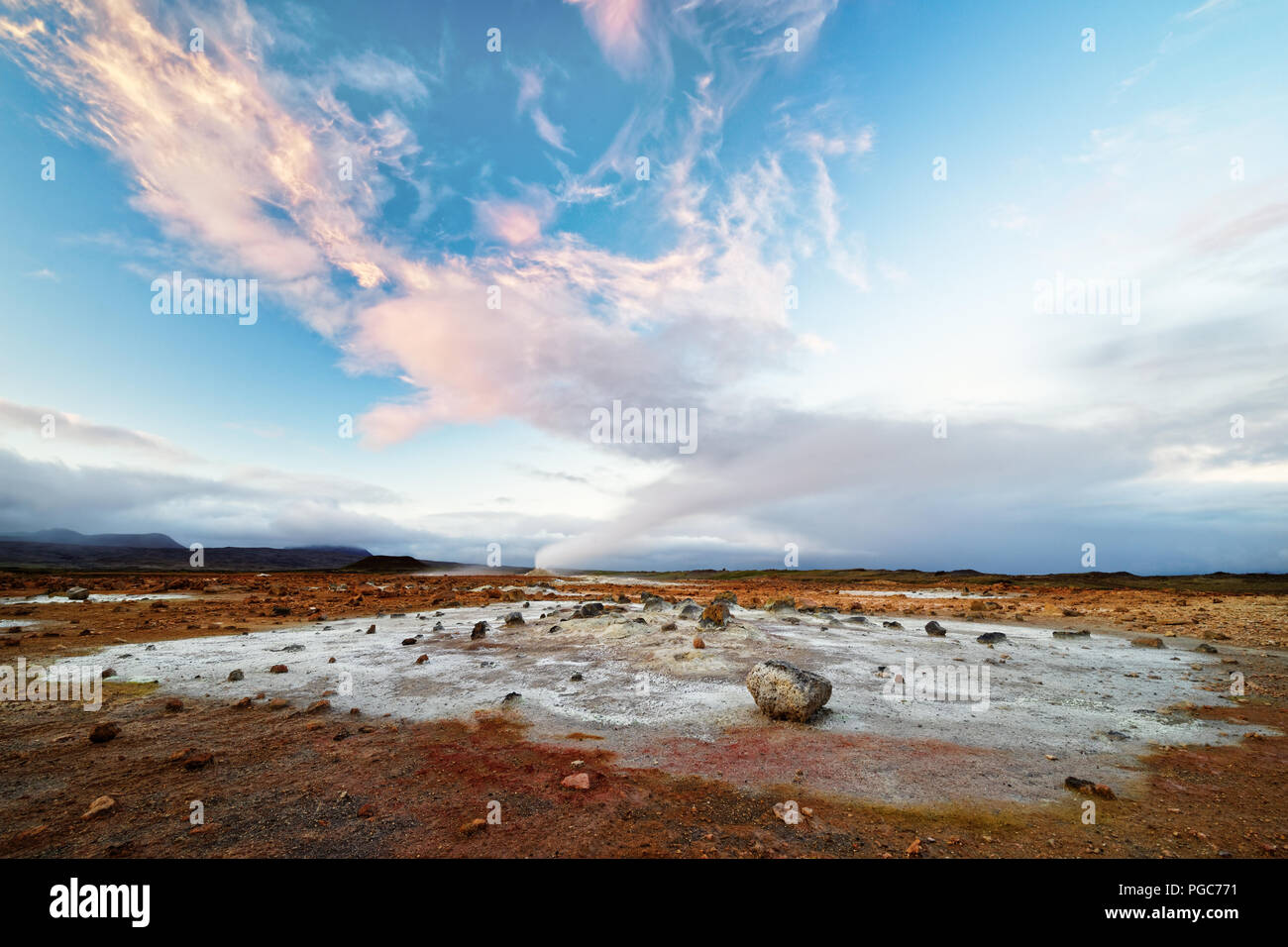 Large vue sur un paysage volcanique de couleur rougeâtre et sol gris clair, l'augmentation de la vapeur, au-dessus de lui un ciel avec un nuage rouge - formation Localisation : Islande, g Banque D'Images